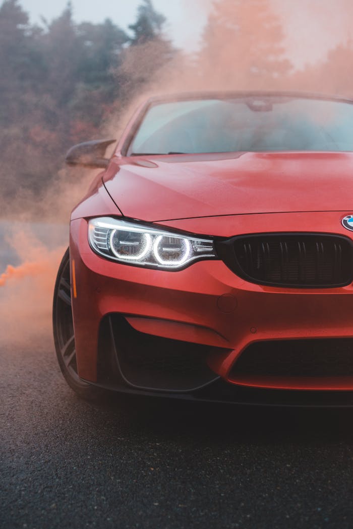 Close-up of a sleek red sports car on a misty road, exuding modern elegance and power.